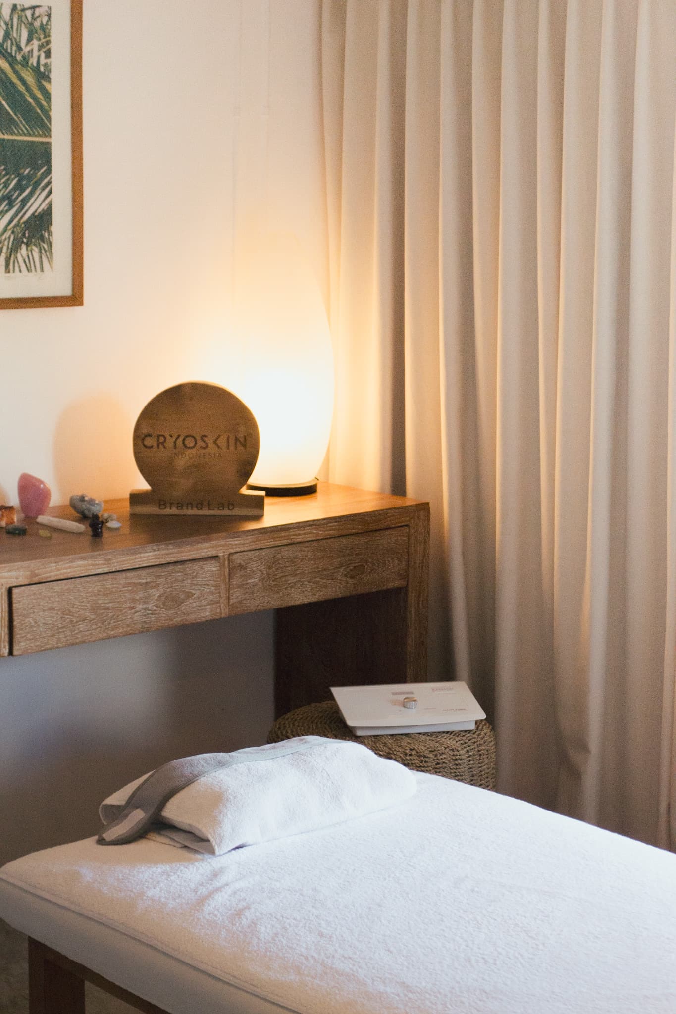 A treatment bed beside the Cryoskin Indonesia Brand Lab sign and a softly lit lamp in the studio.